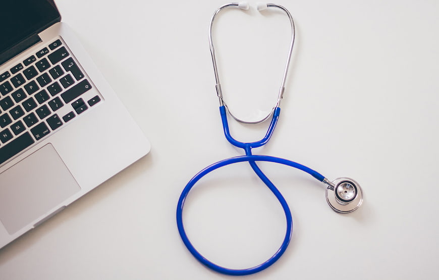 Blue Stethoscope and Laptop on White Desk