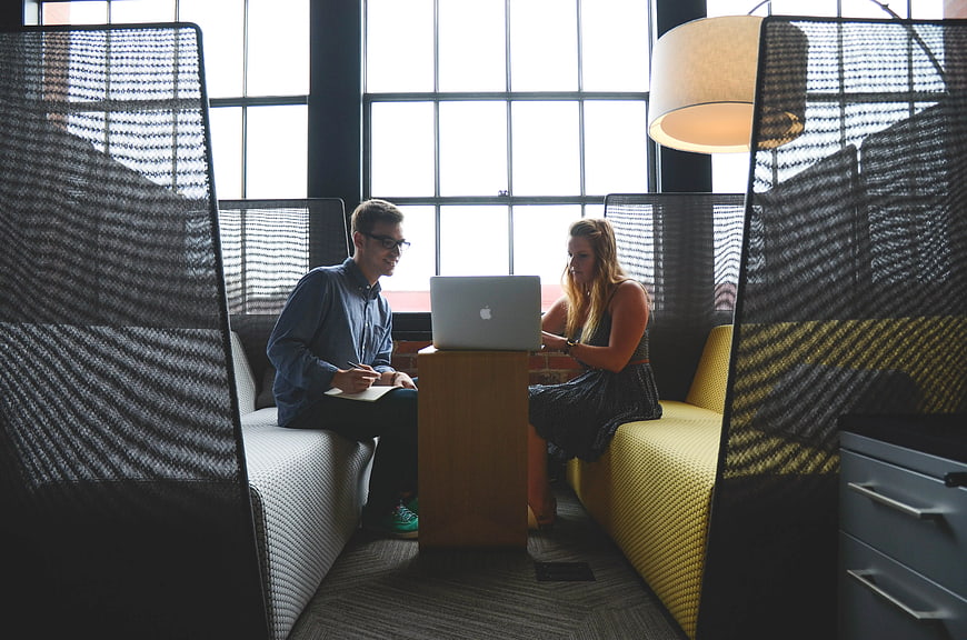 Coworkers collaborating on laptop in modern office