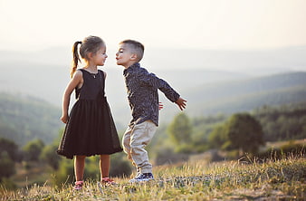 Cute brother and sister about to kiss in a meadow