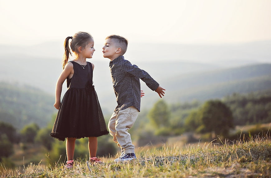 Cute brother and sister about to kiss in a meadow