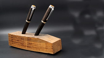 Handcrafted wooden pens in rustic holder on dark background