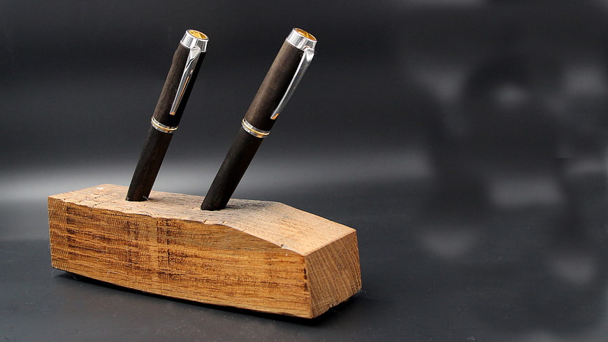 Handcrafted wooden pens in rustic holder on dark background