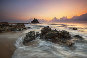 Long Exposure Sunset Seascape with Rocky Shore and Silhouetted Island