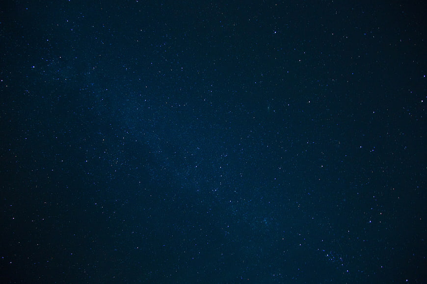 Deep blue night sky filled with stars and faint Milky Way