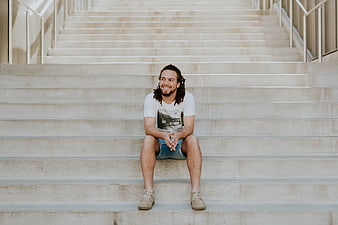 Happy man with dreadlocks sitting on concrete stairs