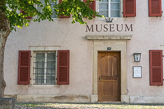 Historic Museum Facade with Red Shutters and Wooden Door