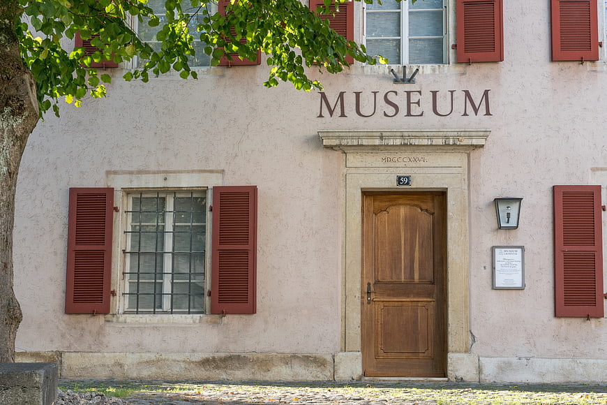 Historic Museum Facade with Red Shutters and Wooden Door