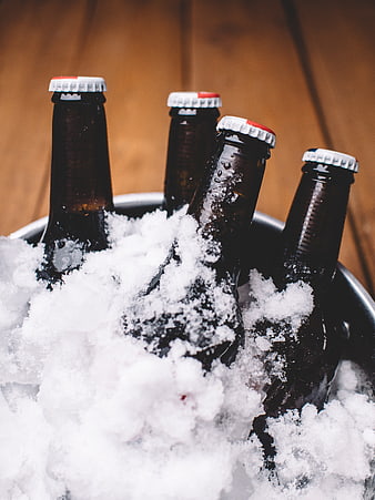 Chilled beer bottles in ice bucket on wooden background