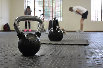 Close-up of 8kg kettlebell on gym floor with blurred workout background