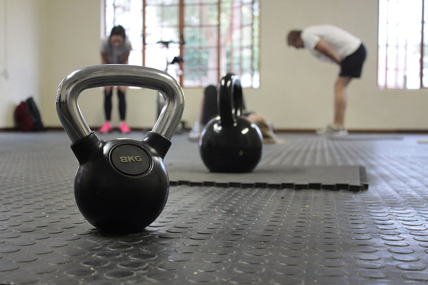 Close-up of 8kg kettlebell on gym floor with blurred workout background