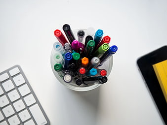 Top View of Colorful Markers in Cup on White Desk