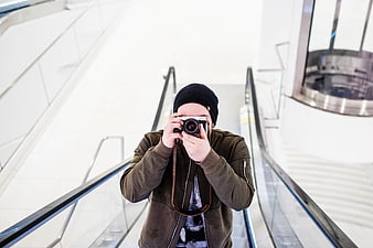 Man with vintage camera taking photo on escalator