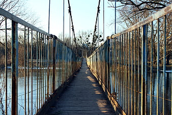 Rusty Suspension Bridge Over River in Winter