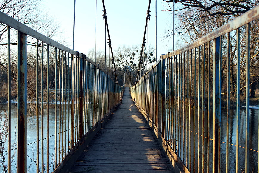 Rusty Suspension Bridge Over River in Winter