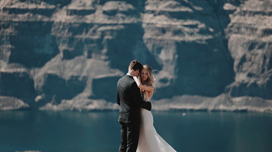 Romantic Wedding Couple Embracing by Lake with Mountains