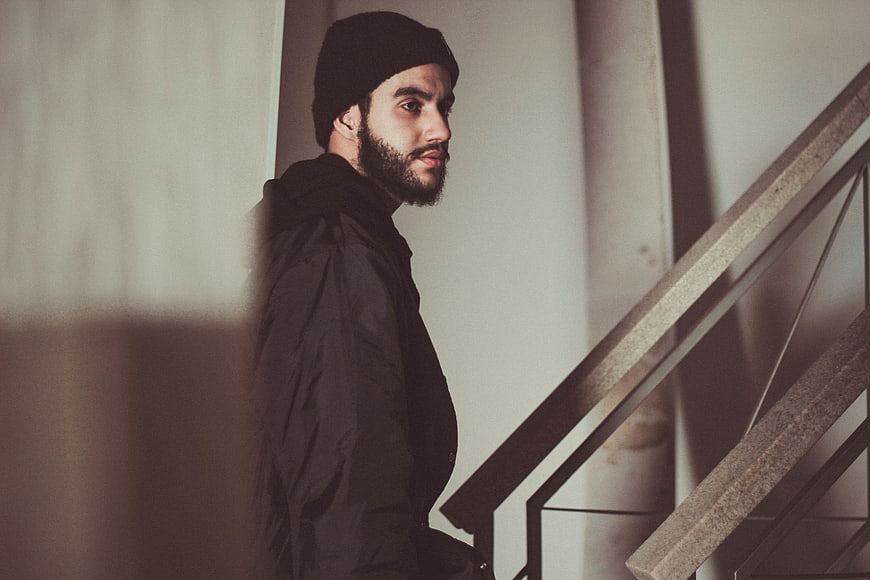 Moody portrait of bearded man in beanie on stairs