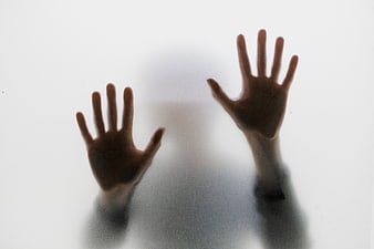 Silhouette of Hands Pressing Against Frosted Glass