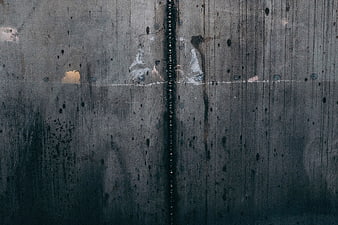 Dark textured concrete wall with vertical seam and weathering