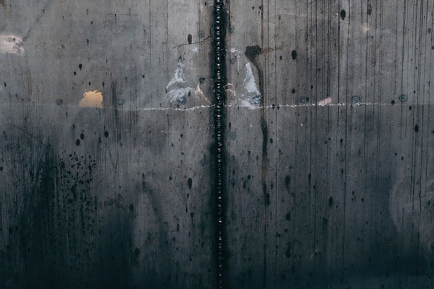 Dark textured concrete wall with vertical seam and weathering