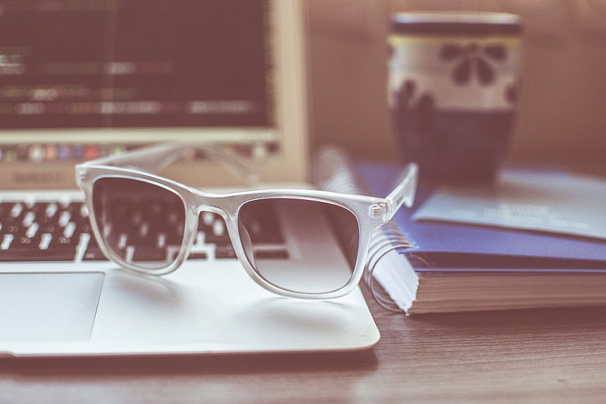 White Sunglasses on Laptop with Coffee and Notebook