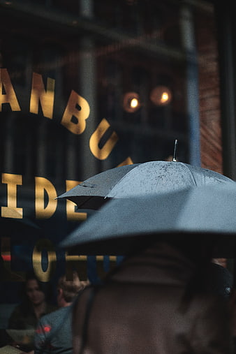 Black Umbrella in Rain with Blurred City Background