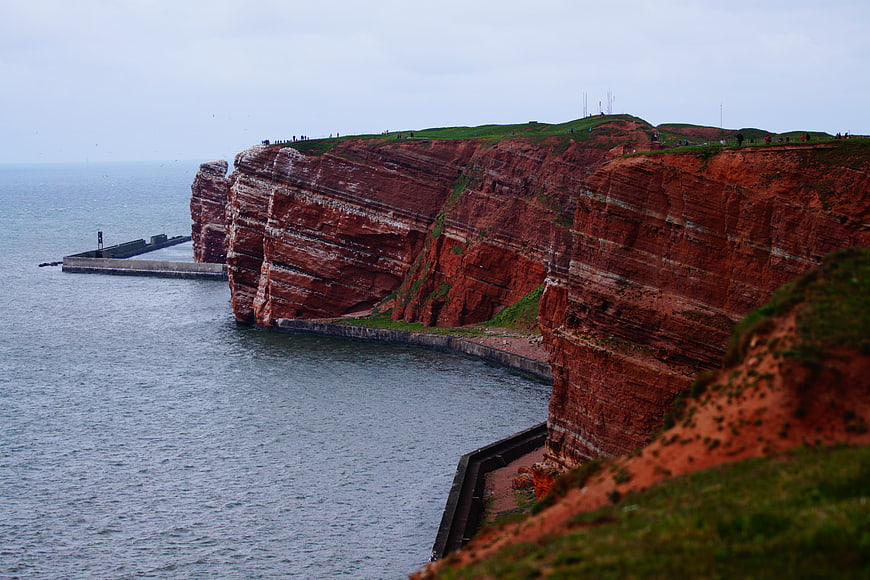 Red sandstone cliffs of Helgoland with harbor and green grass