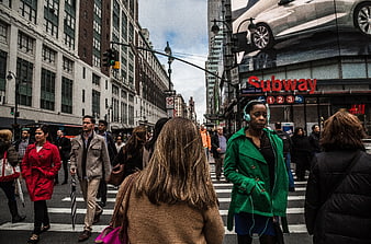 Busy New York City street scene with pedestrians crossing near subway