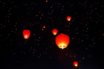 Glowing red sky lanterns floating in a dark night sky