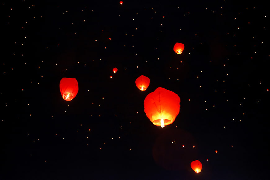 Glowing red sky lanterns floating in a dark night sky