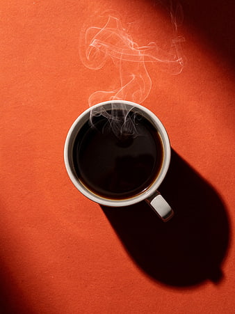 Top View of Steaming Black Coffee in White Mug on Orange Background