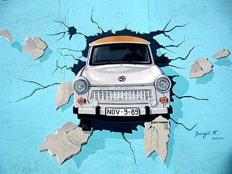 Trabi car mural breaking through blue wall Berlin