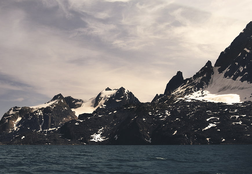 Dramatic Snow-Capped Mountain Peaks Rising from Dark Ocean Waters