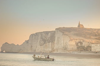 Fishing boat near Etretat cliffs and church at sunrise