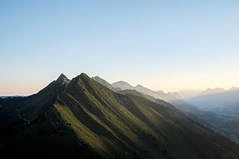 Sunlit Mountain Peaks with Green Slopes and Blue Sky