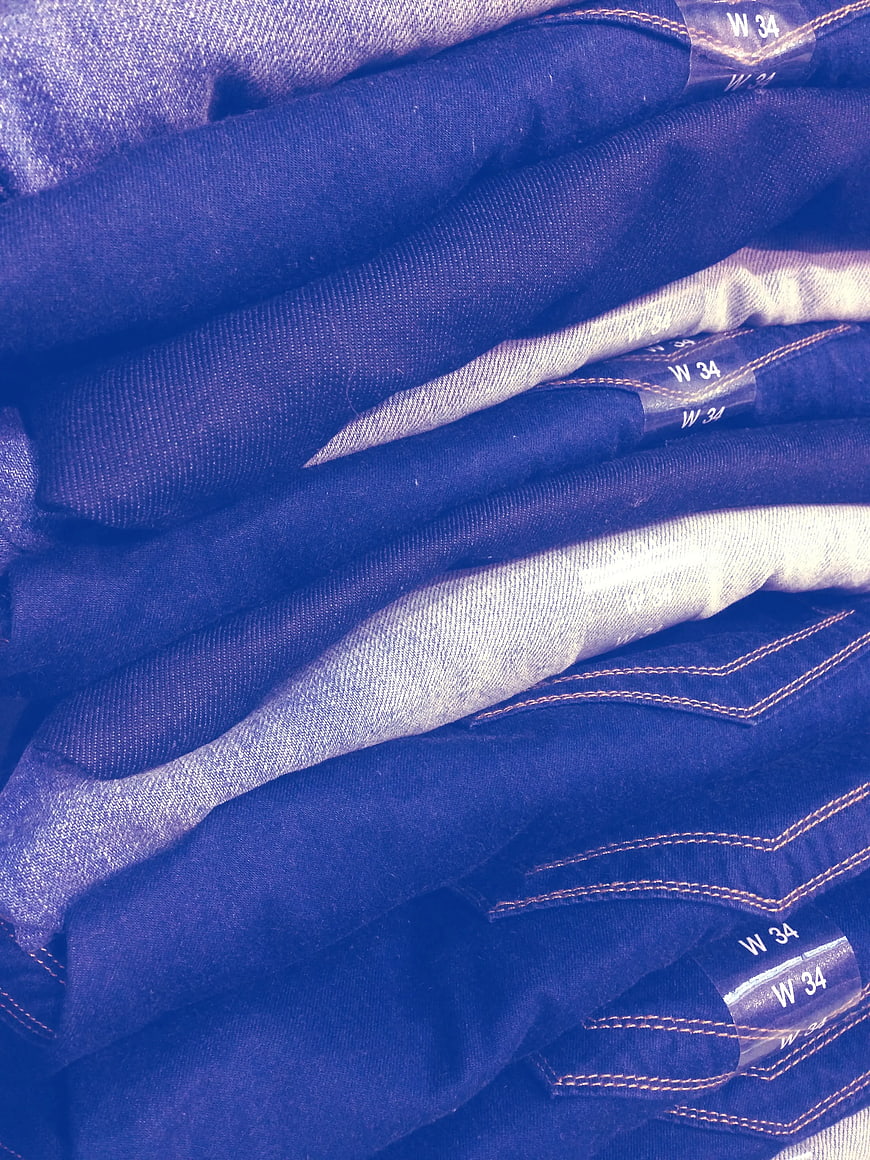 Stack of folded blue jeans with visible size labels