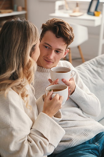 Young couple drinking coffee together on sofa at home