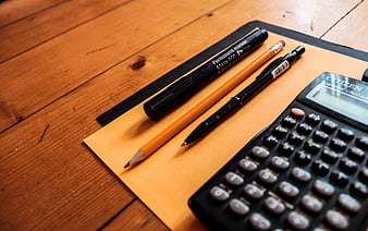 Office Supplies on Wooden Desk with Calculator and Pens