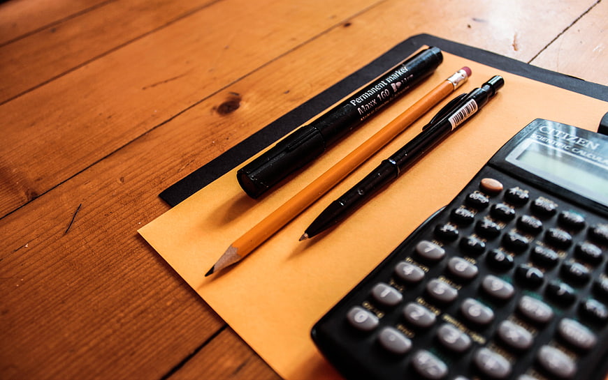 Office Supplies on Wooden Desk with Calculator and Pens