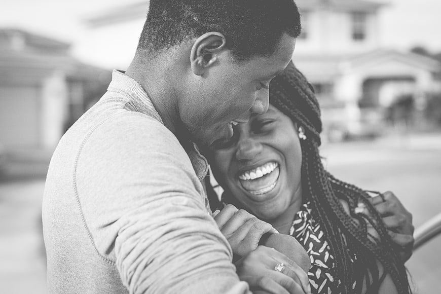 Happy African American couple laughing together outdoors in black and white