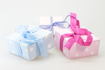 Three pastel polka dot gift boxes with ribbons on white background