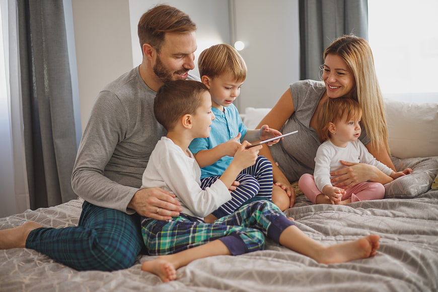 Happy family with tablet on bed in pajamas