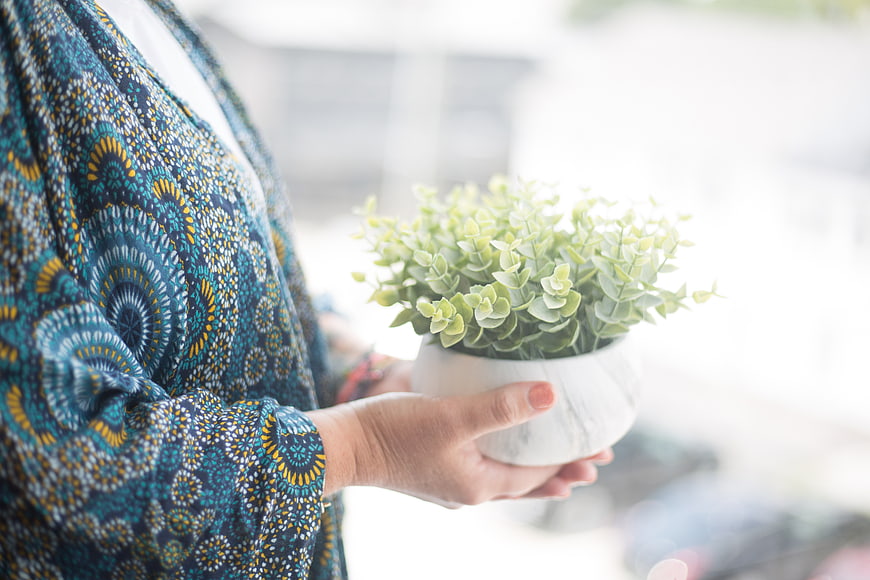 Woman holding small potted plant indoors