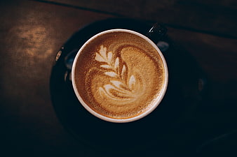 Overhead view of cappuccino with latte art on dark table