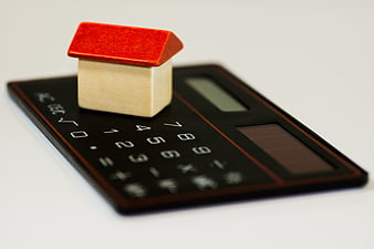 Miniature house model on a black calculator for real estate finance