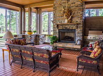 Cozy rustic porch with stone fireplace and wicker furniture