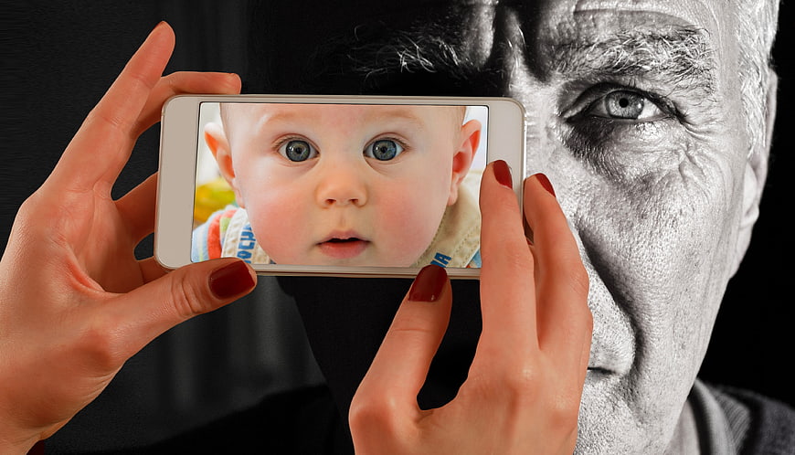 Senior man holding smartphone with baby photo on screen