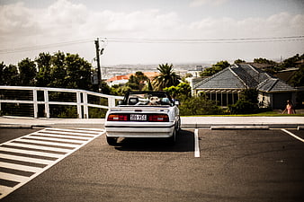 White convertible car parked on suburban street with dog