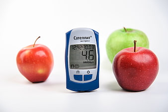 Blood Glucose Meter With Red And Green Apples On White Background