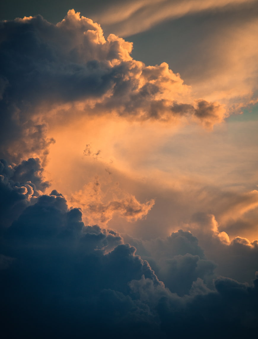 Dramatic sunset clouds with golden light breaking through dark stormy sky