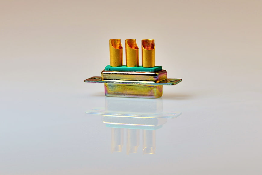 Gold-plated electrical connector with three terminals on white background